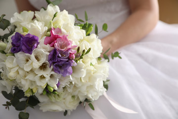 Bride holding beautiful bouquet with spring freesia flowers, closeup