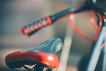 The saddle of a new red sports bike, illuminated by bright summer sunlight. Selective focus.