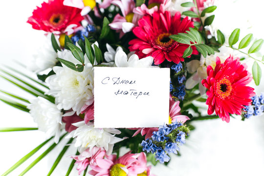 white card for a bouquet with the inscription Happy Mother's Day in russian in a bright beautiful bouquet of flowers