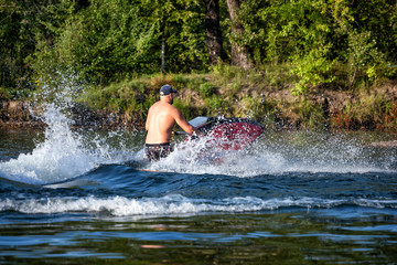 Young man riding water scooter on a river on summer day.