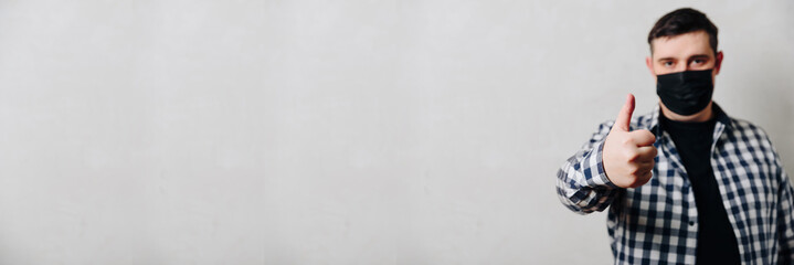 man in a shirt in a black medical mask on a gray background