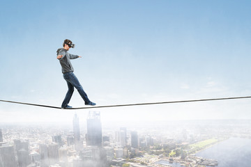 Man wearing virtual reality goggles and balancing on rope