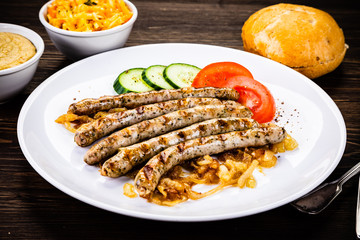 Grilled sausages and vegetables on wooden table
