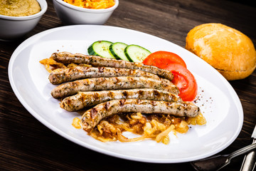 Grilled sausages and vegetables on wooden table