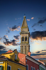 n old church bell tower over brightly colored homes in Burano