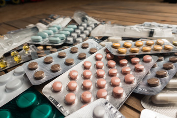 Closeup shot of different pills on table with tablets , pharmaceutical industry concept