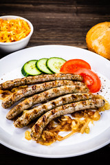 Grilled sausages and vegetables on wooden table