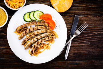 Grilled sausages and vegetables on wooden table