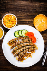 Grilled sausages and vegetables on wooden table