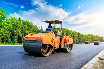 Construction site is laying new asphalt road pavement,road construction workers and road construction machinery scene.highway construction site landscape.