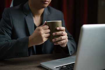 Man working from home using computer and drinking cup of tea, closeup portrait indoor.