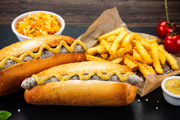 Hot dogs, French fries and vegetables on black stone board