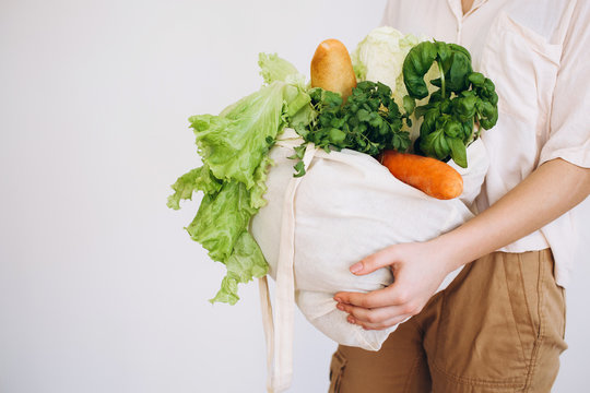 Hand with an eco bag with vegetables.Young hipster lifestyle girl holding textile glocery bag with vegetables. Zero waste food shopping. eco natural concept
