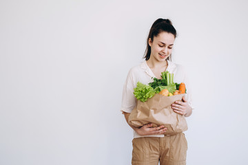 Hand with an eco paper bag with vegetables.Young hipster lifestyle girl holding paper bag with vegetables. Zero waste food shopping. eco natural concept