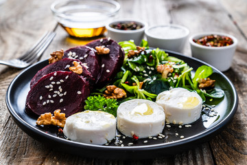  Beetroot salad with goat cheese on wooden background