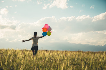Cheering young asian woman on grassland with colored balloons