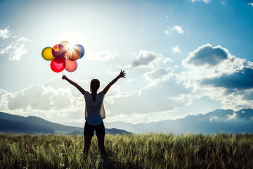 Cheering young asian woman on grassland with colored balloons - obrazy, fototapety, plakaty
