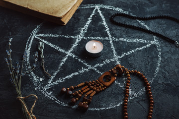 Pentagram circle with a candle , an old book and amulets on the table . The concept of occultism ,...