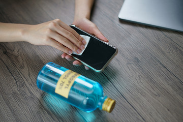 Hand pouring ethyl alcohol from bottle  into a cotton piece for clean mobile phone, corona virus or Covid-19 protection.