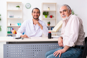 Fototapeta premium Old man visiting young male doctor cardiologist