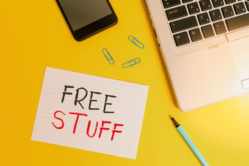 Writing note showing Free Stuff. Business concept for something that is given to you without you having to pay for it Trendy laptop smartphone marker paper sheet clips colored background