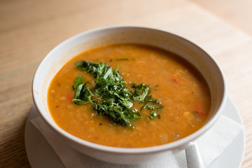 Cream soup garnished with green herbs in white bowl