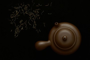Clay teapot and green tea on black background. Healthy drink 
