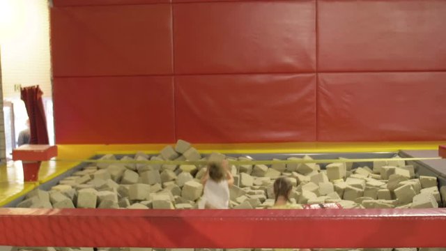 Two girlfriends are jumping in pool with sponges. Children have fun in Trampolin Park.