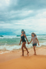 family relationship, mother with daughter are walking on the beach and smiling. vacation concept, free space	