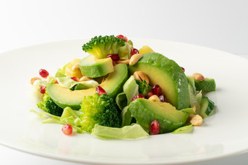 Green Salad with Avocado, Cucumber and Nuts on White Plate