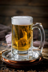 Light frothing beer in a glass, on an old background.