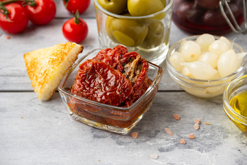 Italian antipasti, olives, capers, sun-dried tomatoes , olive oil, bread (ciabatta, baguette, croutons). Mediterranean assortment of delicious food, wine snacks