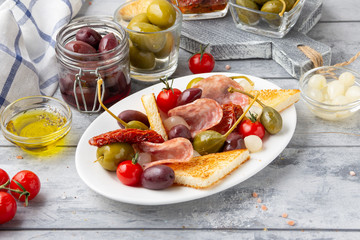Italian antipasti, olives, capers, sun-dried tomatoes , olive oil, bread (ciabatta, baguette, croutons). Mediterranean assortment of delicious food, wine snacks