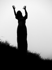 Silhouette of a statue of a woman, her hands outstretched in prayer. Waiting on a shore, Rosses point, coutny Sligo, Ireland.