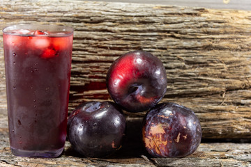 Glass of fresh plum juice and fruits (Prunus domestica)