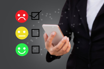 Business women select happy face emoticon on virtual touch screen at smartphone