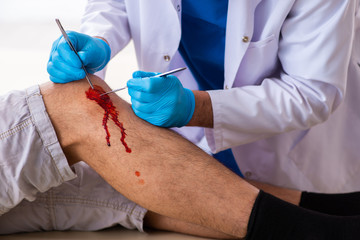 Leg injured man visiting old doctor in first aid concept