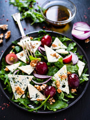 Fresh salad - blue cheese, grapes, spinach, walnuts on black stone board