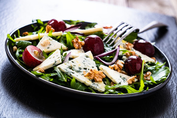 Fresh salad - blue cheese, grapes, spinach, walnuts on black stone board
