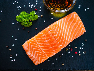 Fresh raw salmon steak on black stone board