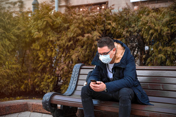 Adult man in street. Lifestyle concept photo with copy space. Picture of professional who using disposable face mask with modern personal smartphone