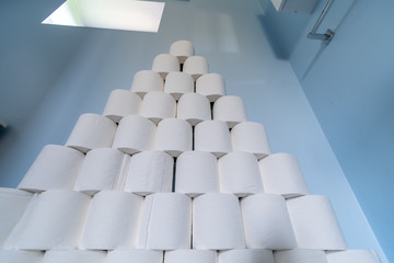 A huge pile of toilet paper stacked up next to a toilet