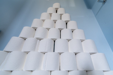 A huge pile of toilet paper stacked up next to a toilet