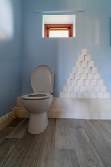 A huge pile of toilet paper stacked up next to a toilet
