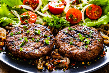 Barbecue steaks with vegetables on wooden background