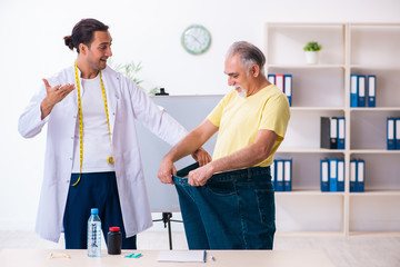 Fototapeta premium Doctor dietician and happy patient wearing large trousers