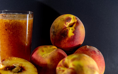 Glass of peach juice (Prunus persica L.) and fresh fruit
