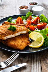 Pork chops with lemon and vegetable salad on wooden background
