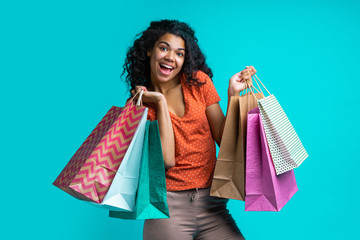 Fototapeta na wymiar Attractive young dark skinned woman with a bunch of shopping bags