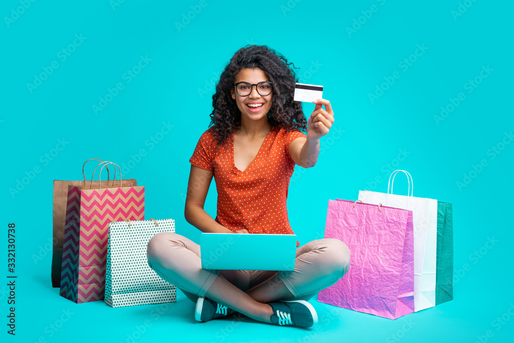 Wall mural Attractive young dark skinned woman with a bunch of shopping bags